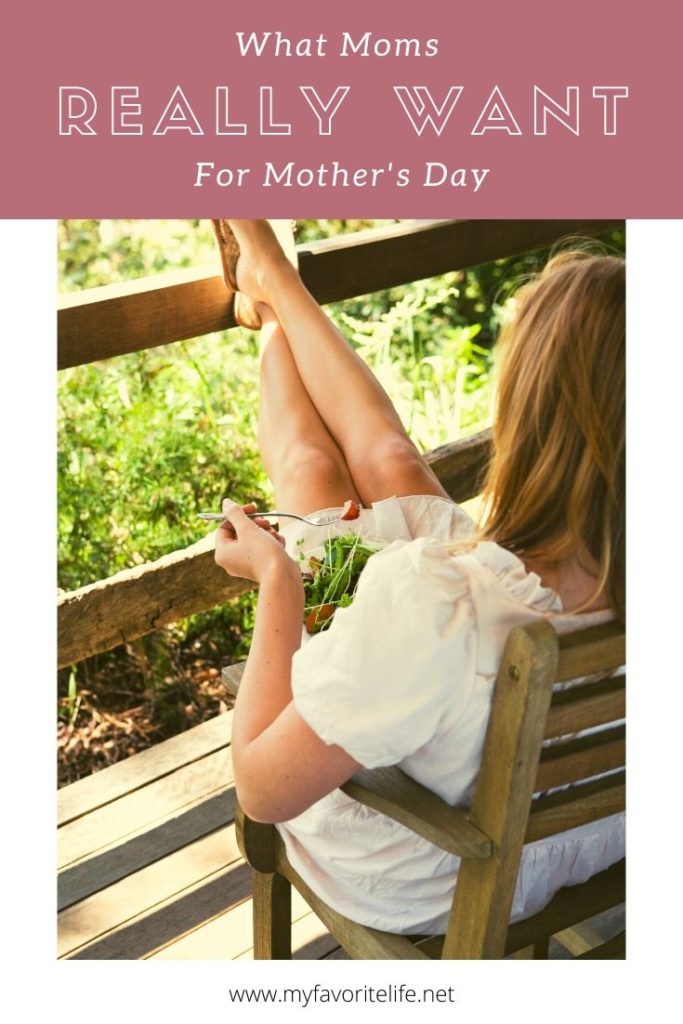 Woman sitting on a wooden chair on her deck with feet up on the wood railing relaxing