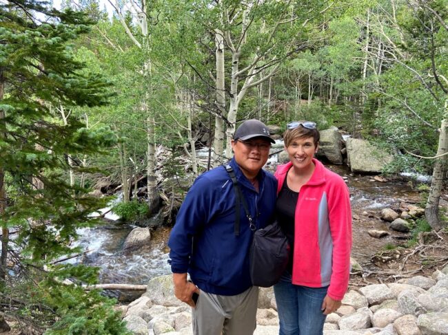 Me with my husband in front of running water an trees